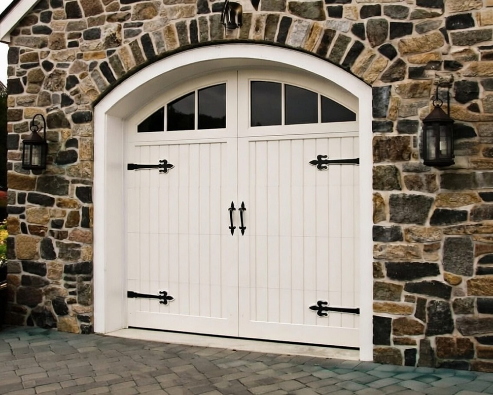 Elegant White Arched Garage Door With Carriage House Style, Vertical Paneling, Black Wrought Iron Hardware And Strap Hinges, Set In A Stone Facade Home – Installed By Lead Contractor Dmytro Shevchenko, North West Chicago