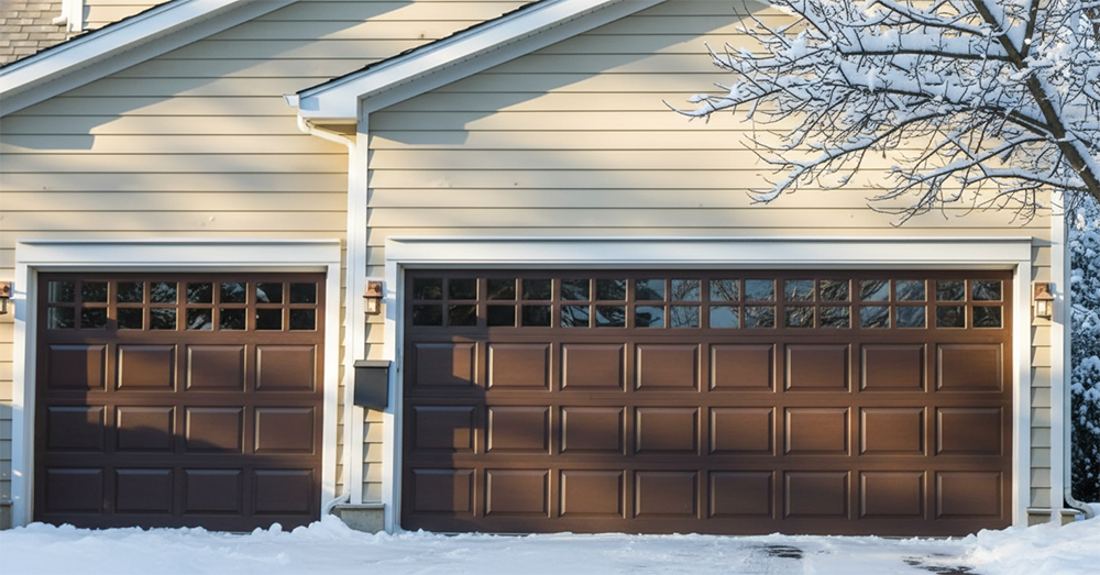 A Beige Home Featuring Two Classic Chocolate Brown Sectional Garage Doors With Upper Windows, Captured On A Sunny Winter Day With Snow On The Ground. This Installation Showcases The Durable Residential Garage Door Options Provided By Lead Contractor Dmytro Shevchenko For Homeowners In North West Chicago.