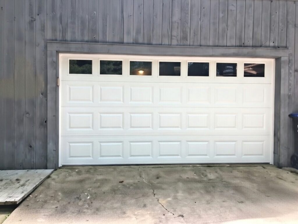 Classic White Raised-Panel Garage Door With Top-Row Windows Set Against Grey Wood Siding, Installed By Lead Contractor Dmytro Shevchenko In North West Chicago.