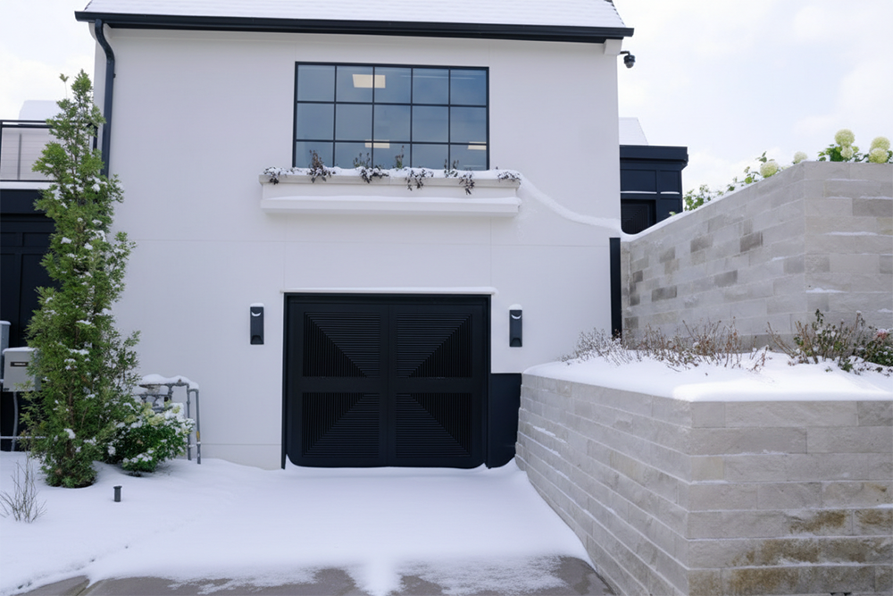 A Modern White Home Featuring A Custom Black Geometric Garage Door Surrounded By A Snowy Landscape. The Design Showcases Premium Garage Door Options Installed By Lead Contractor Dmytro Shevchenko In North West Chicago, Blending Contemporary Style With Winter Durability.