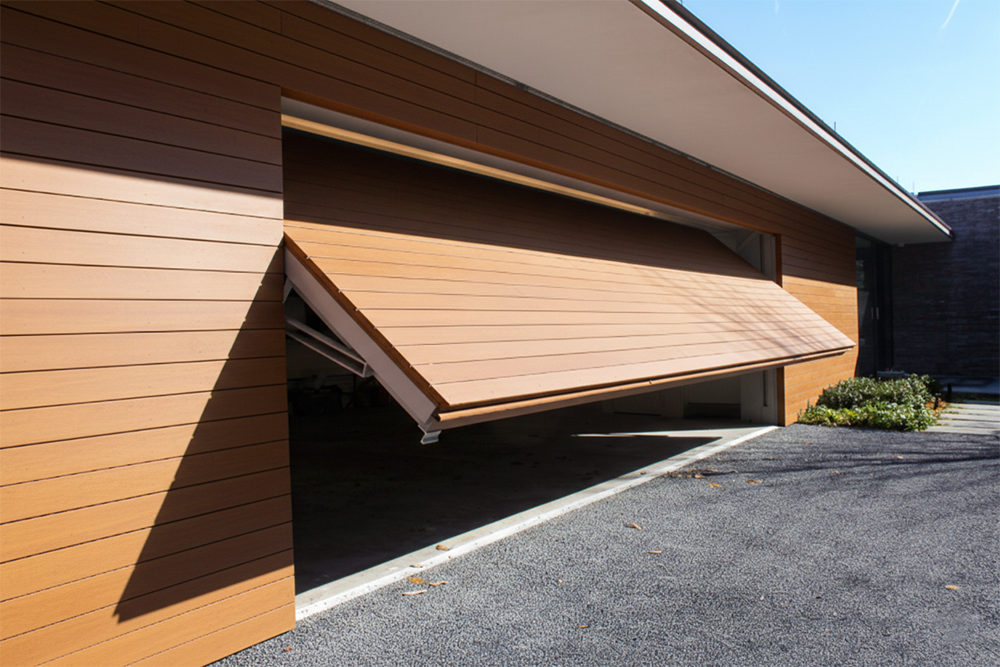 A Sleek, Modern Wood-Cladded Tilt-Up Garage Door With Horizontal Panels Partially Open On A Contemporary Home, Showcasing Premium Garage Door Options Provided By Lead Contractor Dmytro Shevchenko In The North West Chicago Area.