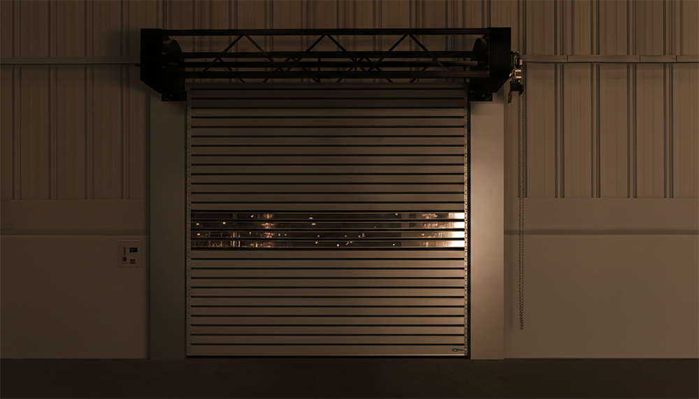 An Industrial Roll-Up Metal Garage Door With A Clear Vision Window Panel In A Warehouse Setting, Showcasing Heavy-Duty Garage Door Options Provided By Lead Contractor Dmytro Shevchenko In North West Chicago.