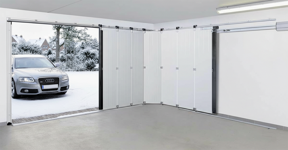 A Modern White Side-Sliding Garage Door Installed In A Spacious Garage, Curving Along The Interior Wall. Outside, A Silver Car Is Parked In A Snowy Driveway. This Unique Mechanism Highlights The Diverse Garage Door Options Available Through Lead Contractor Dmytro Shevchenko For Homes In North West Chicago.
