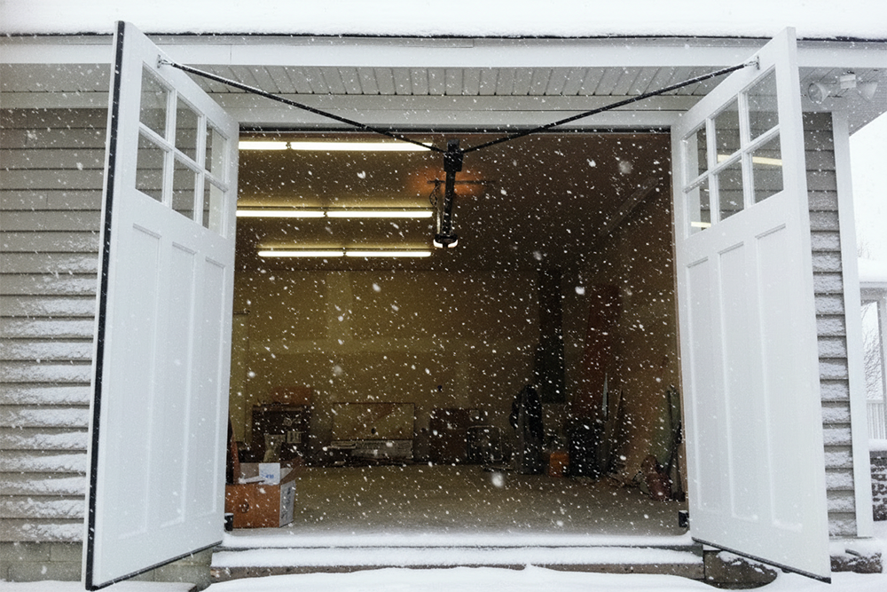 White Swing-Out Carriage Style Garage Doors Open During A Snowfall, Demonstrating Unique Garage Door Options Installed By Lead Contractor Dmytro Shevchenko For Homes In North West Chicago.