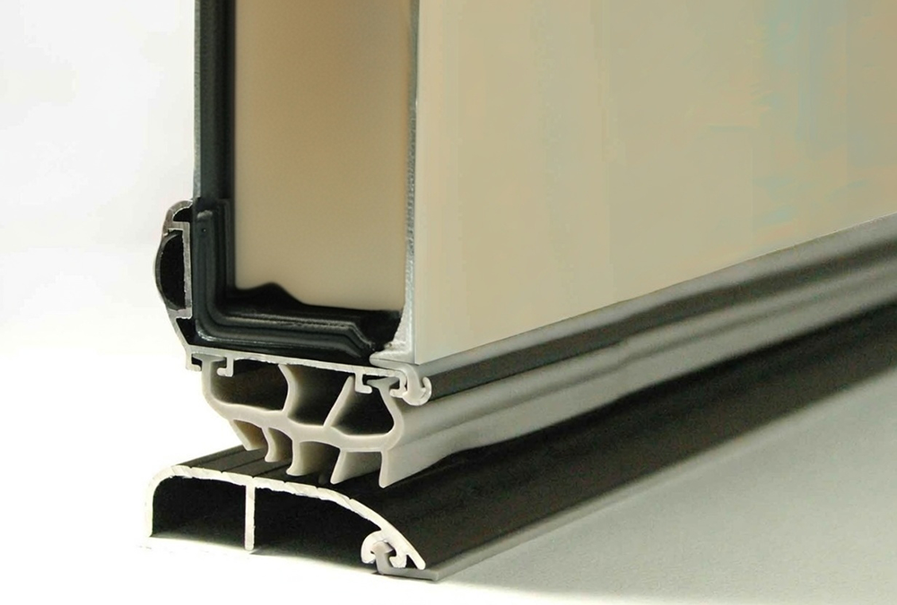 Residential Garage Door Types: A Complete 2026 Guide For Chicago Homeowners Close-Up Detail Of Residential Garage Door Bottom Weather Seal And Aluminum Retainer With Dual Epdm Rubber Bulb Seals, Gray Pvc Bottom Astragal, Thermal Break Design On Insulated Sectional Panel, North West Chicago. Lead Contractor Dmytro Shevchenko – High-Quality Residential Garage Door Types.