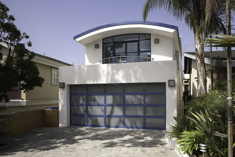 Residential Garage Door Designs: The Ultimate 2026 Style &Amp; Performance Guide Striking Modern Residential Garage Door Designs In Bold Blue Frame With Full Frosted Glass Panels On A Contemporary White Stucco Home Featuring Curved Blue Roofline And Large Upper Windows, Installed By Lead Contractor Dmytro Shevchenko In North West Chicago