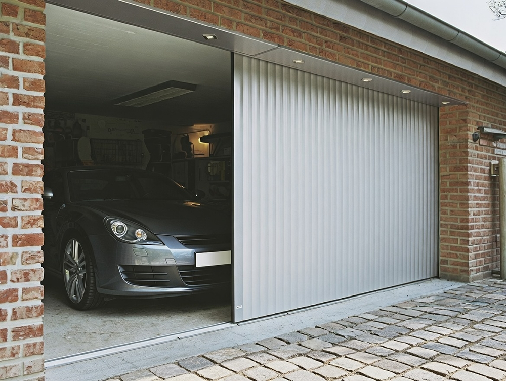Garage Door Opening Styles: Choosing The Right Movement For Your Home Example Of Garage Door Opening Styles Featuring A Sleek Side-Sliding (Horizontal Sliding) Sectional Garage Door In Silver/Aluminum Finish, Partially Open To Show The Interior With A Parked Car, Installed By Lead Contractor Dmytro Shevchenko In North West Chicago.