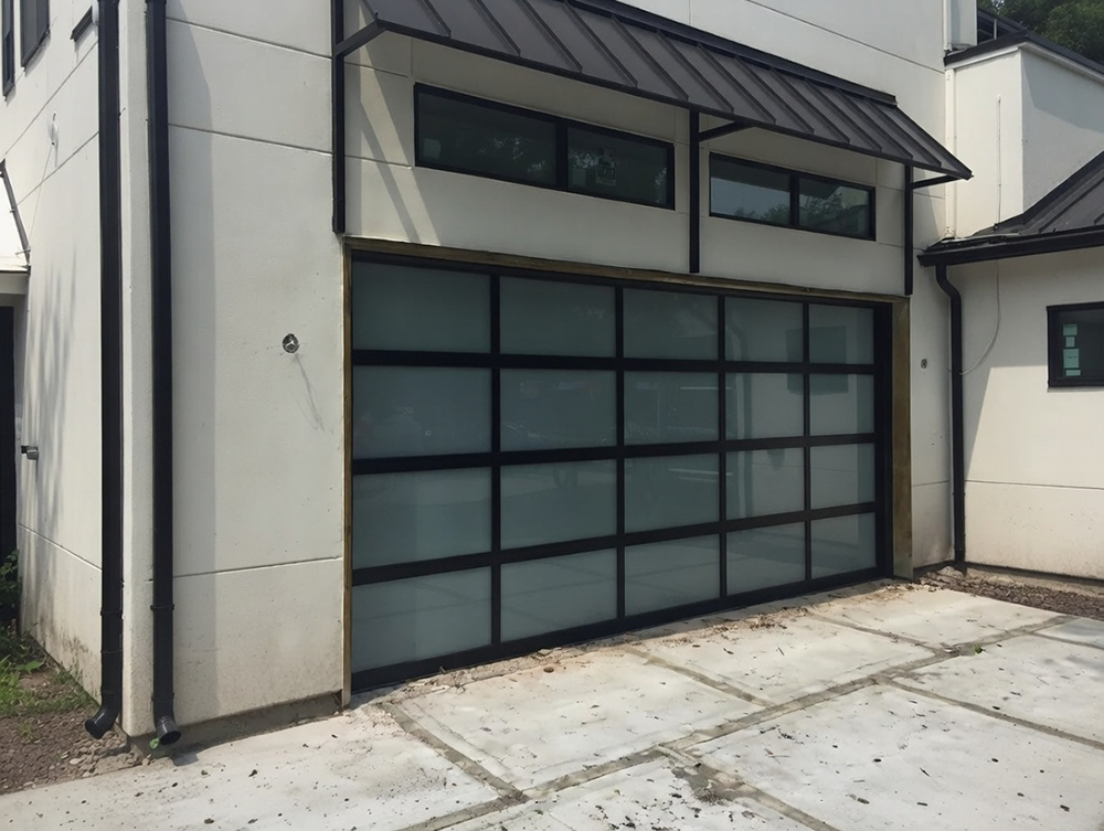 Types Of Garage Doors With Pictures: A Visual Gallery For 2026 Modern Full-View Glass Sectional Garage Door With Black Grid Frame And Frosted Panels Under A Metal Awning On A Contemporary White Home, Excellent Example Of Types Of Garage Doors With Pictures – Installed By Lead Contractor Dmytro Shevchenko, North West Chicago