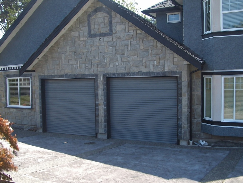 What Is A Garage Door Called? A Guide To Names And Terminology Example Of Double Roll-Up (Roller) Garage Doors (Commonly Called Roll-Up Garage Doors Or Roller Shutter Garage Doors) In Gray Finish, Installed Side-By-Side On A Modern Two-Story Home Exterior With Stone Facade, By Lead Contractor Dmytro Shevchenko In North West Chicago. What Is A Garage Door Called? This Type Is Known As A Roll-Up Garage Door.